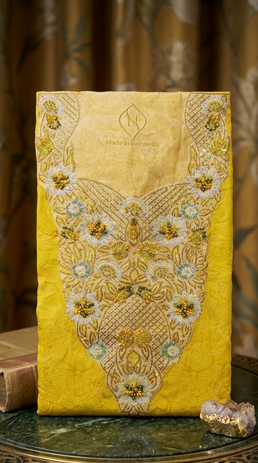 Yellow embroidered clutch on a decorative surface with a blurred background